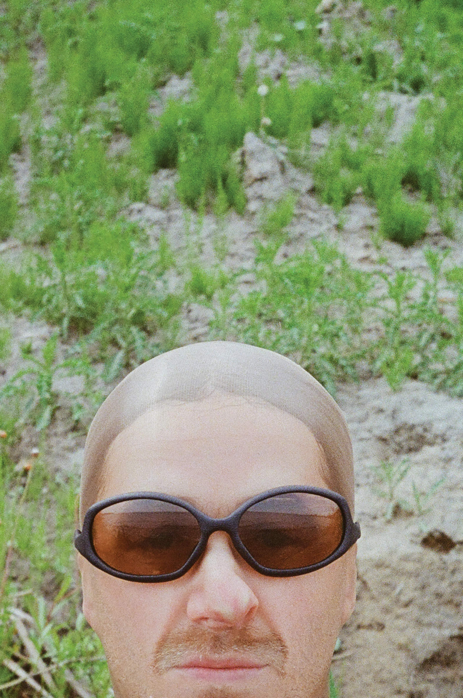 3D render of a bald model wearing black sunglasses with transparent grey lenses