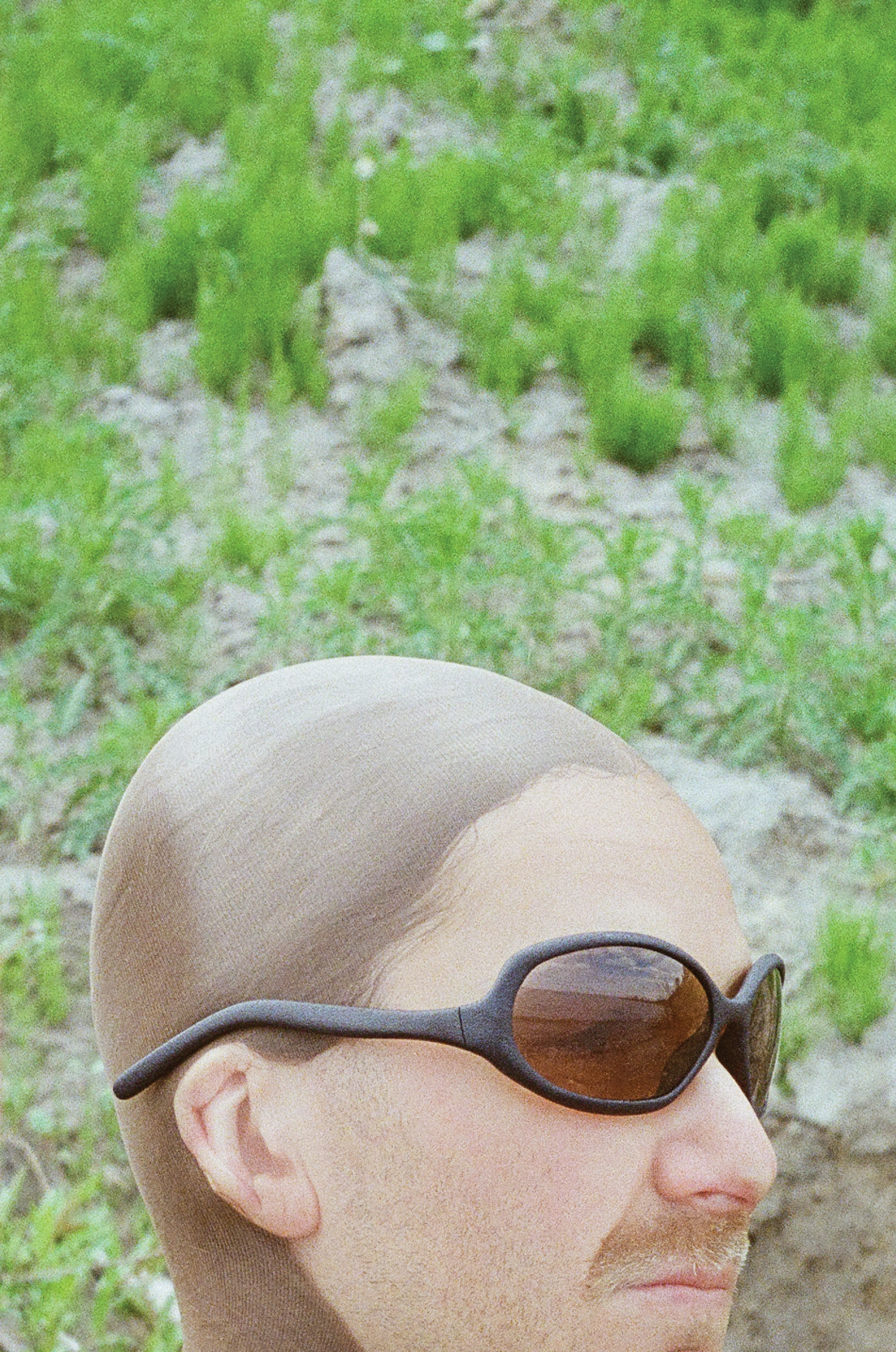 3D render of a bald model wearing black sunglasses with transparent grey lenses