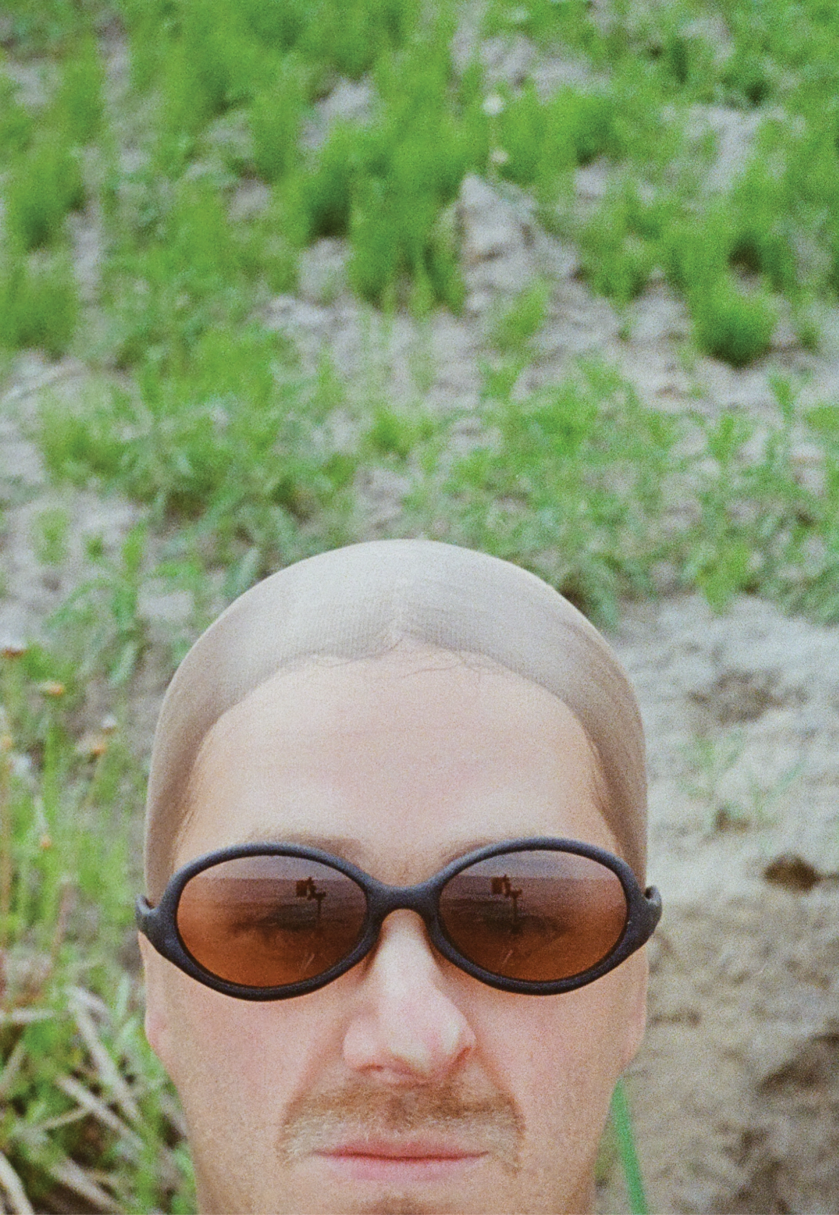 3D render of a bald model wearing black sunglasses with transparent grey lenses