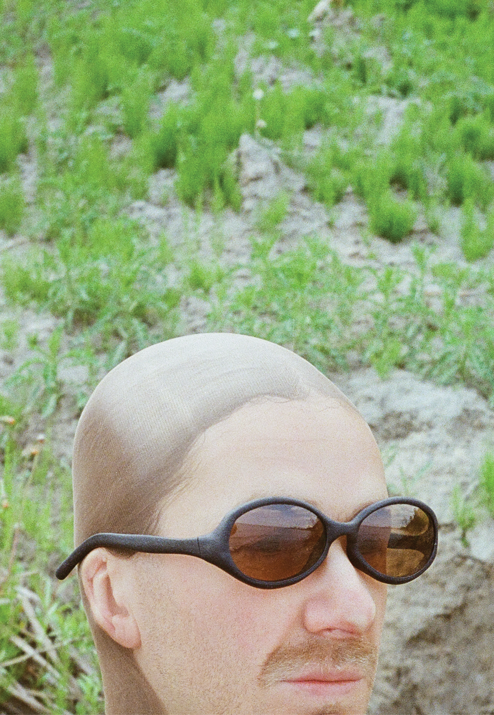 3D render of a bald model wearing black sunglasses with transparent grey lenses