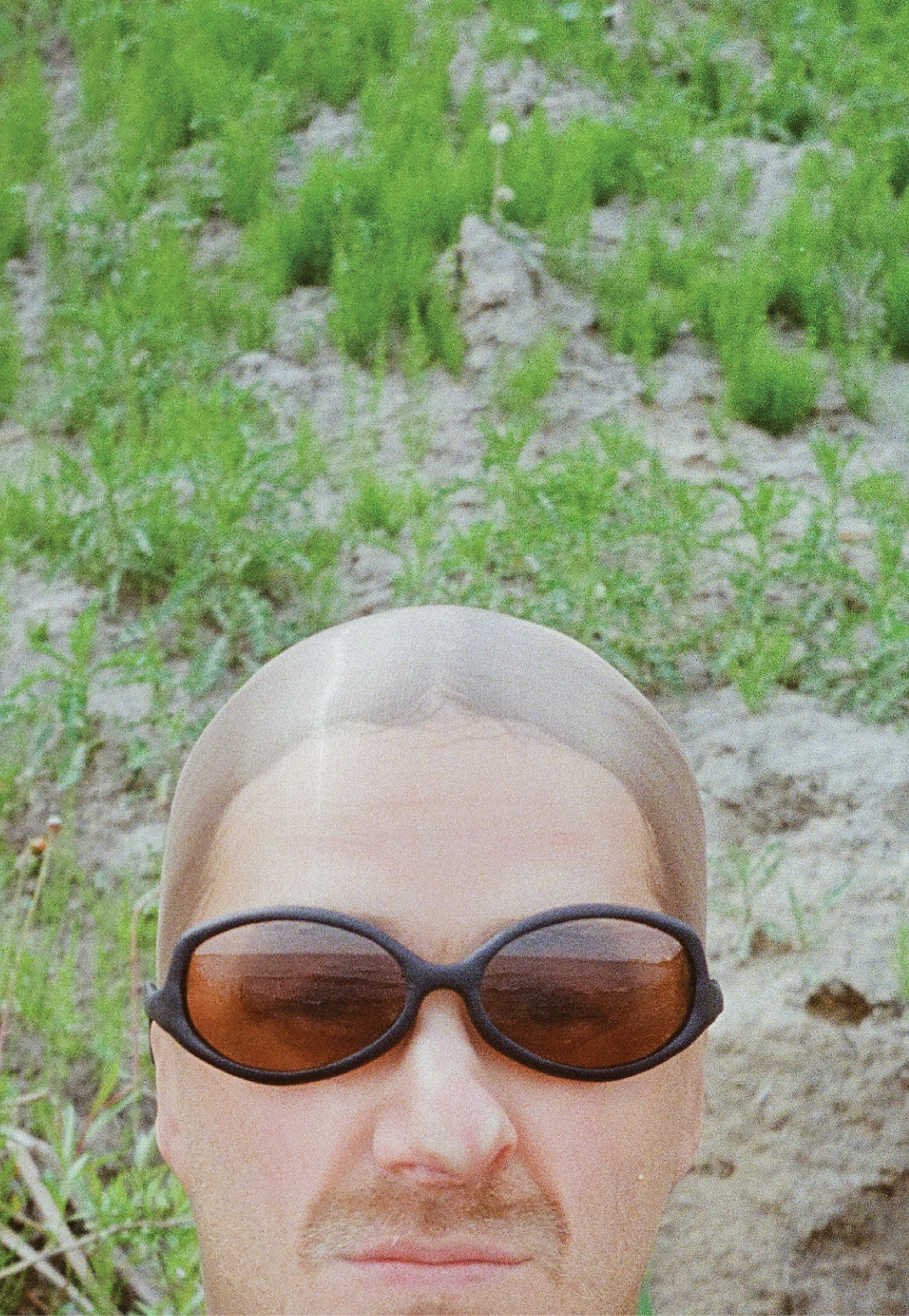 3D render of a bald model wearing black sunglasses with transparent grey lenses