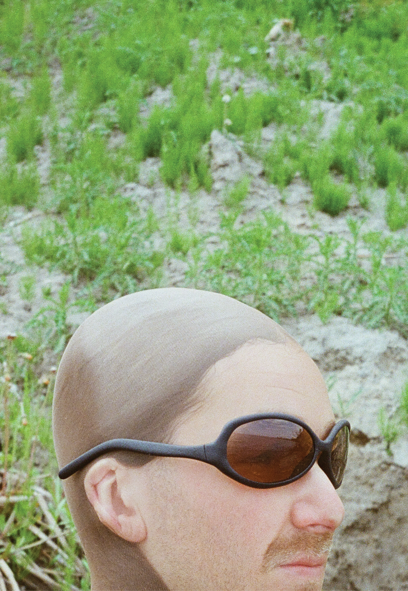 3D render of a bald model wearing black sunglasses with transparent grey lenses